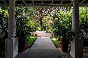 A garden pathway with white columns, surrounded by lush greenery and potted plants. - Staymaster Villa Anasoh 4BHK (Vagator)