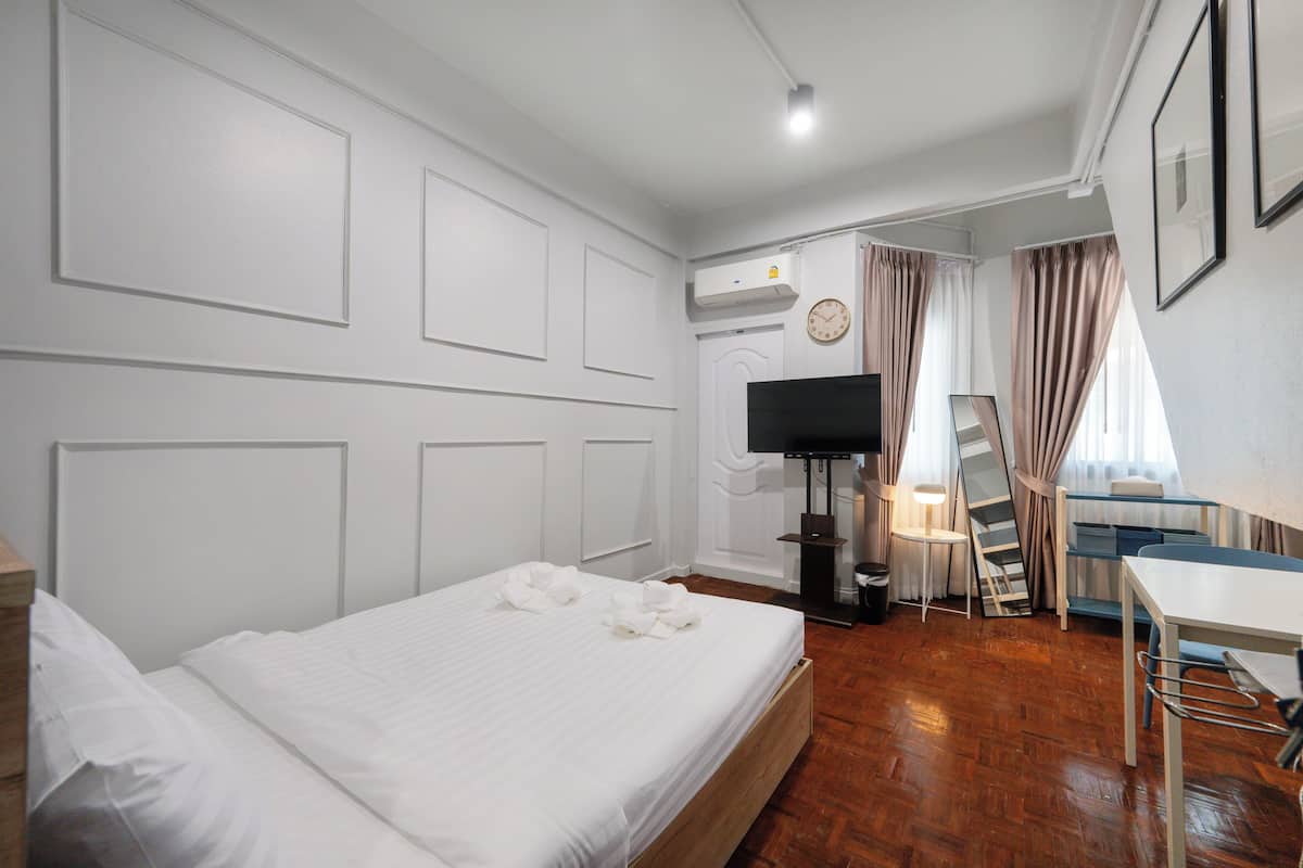 A hotel room with a bed, a desk, a TV, and a window with curtains.