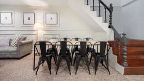 A living room with a sofa, a dining table with chairs, a staircase, and framed pictures on the wall. - Arun Sa Wad House Sukhumvit 2 Guests (Bangkok)