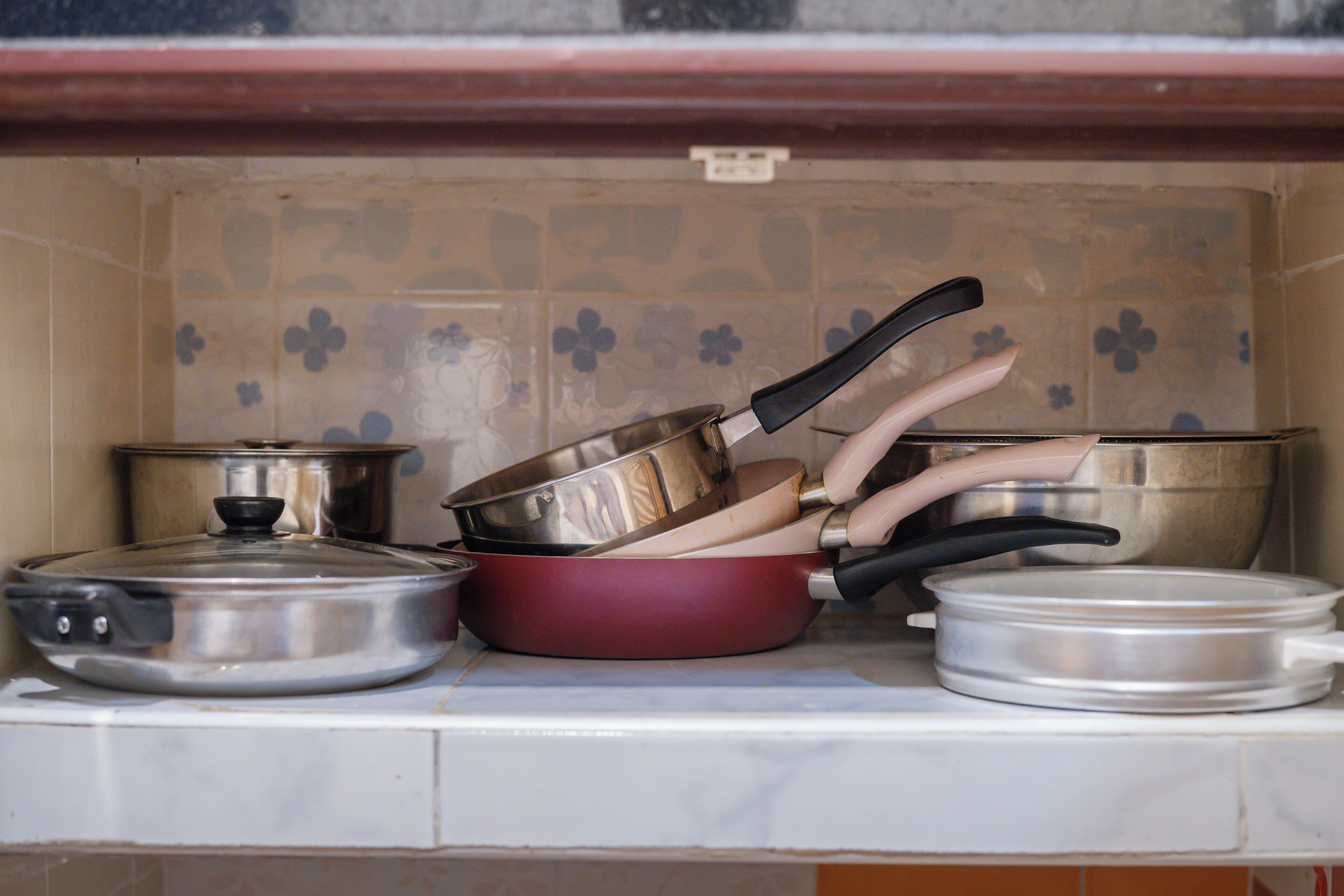 Una cocina con varias ollas y sartenes apiladas sobre una encimera.