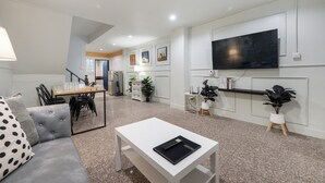 A modern living room with a sofa, coffee table, TV, and dining area. - Arun Sa Wad House Sukhumvit 2 Guests (Bangkok)