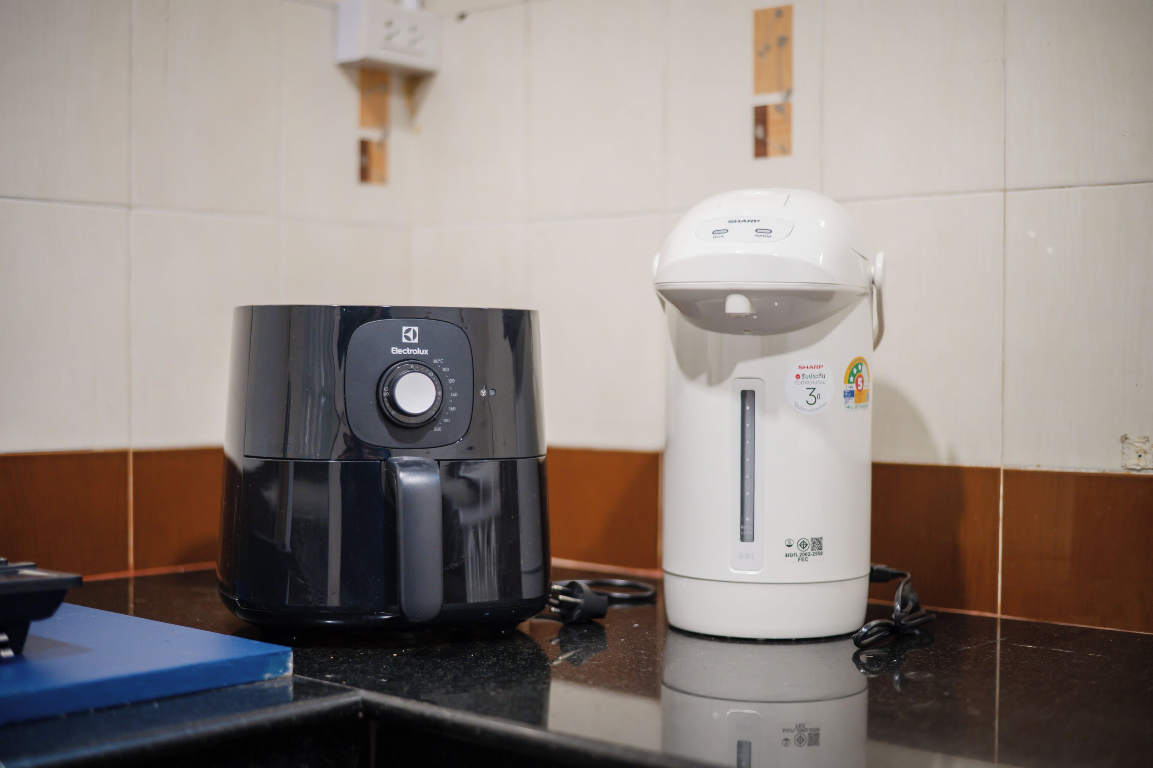 Eine Küche mit einer schwarzen Electrolux-Kaffeemaschine und einer weißen Kaffeemaschine auf der Arbeitsfläche.