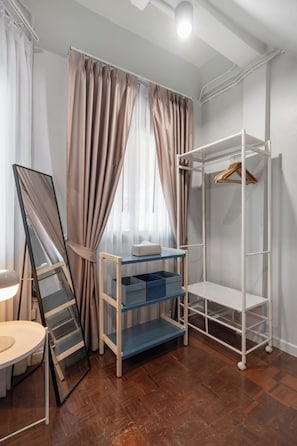 Quarto com beliche, escrivaninha, cadeira e janela com cortinas.