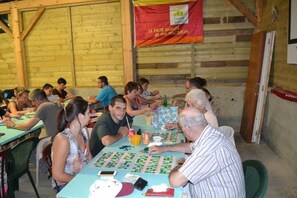 A group of people playing board games at a wooden table in a rustic setting. - Camping 4 étoiles - Piscine  - ccbecda (Gourdon)