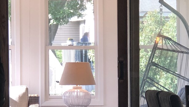 Una stanza con un tavolo, una lampada, un cesto in vimini e una sedia.
