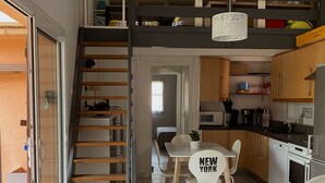 Una cocina moderna con armarios de madera, un comedor con mesa y sillas, y una escalera que lleva a un nivel superior.