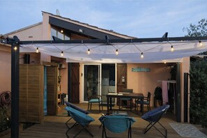 Eine überdachte Terrasse im Freien mit Tisch und Stühlen, einer Lichterkette und einem Schild mit der Aufschrift 'SOUTH BEACH'.