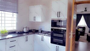 Una cocina moderna con armarios blancos, estufa, horno y una ventana con persianas.