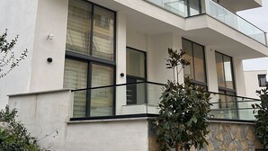 A multi-story building with balconies, large windows, and a stone base. - GoldApartment  (Sarandë)