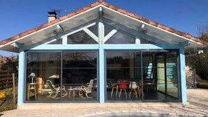 Ein modernes Haus mit einer gläsernen Veranda, einem Schwimmbad und einem roten Ziegeldach.