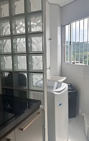 Una cocina con un ventanal grande, un refrigerador blanco y una encimera negra.
