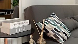 A modern living room with a sofa, a coffee table with a book, and abstract art on the wall. - Residencial Felicita (Barueri)