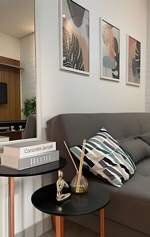 A modern living room with a sofa, a coffee table with a book, and abstract art on the wall.