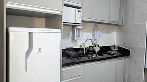 A compact kitchen with a refrigerator, microwave, and stove.