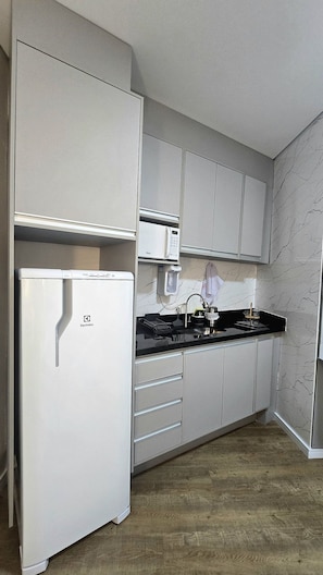 Una cocina compacta con refrigerador, microondas y estufa.