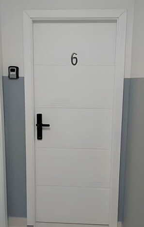 A white door with the number 6, a black door handle, and a small object on the left side.