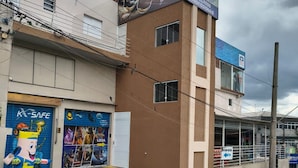 A building with a sign for 'LOJA DE FABRICA' and 'LOJA DE FÁBRICA,' a blue storefront, and a mascot figure outside.