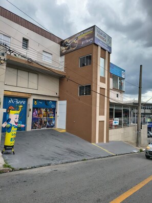 A building with a sign for 'LOJA DE FABRICA' and 'LOJA DE FÁBRICA,' a blue storefront, and a mascot figure outside.