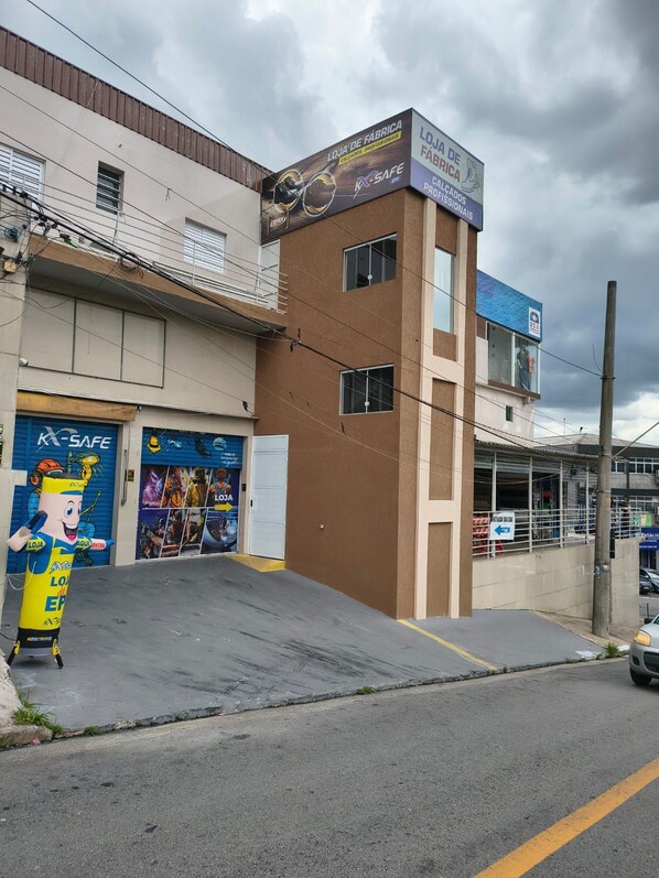 A building with a sign for 'LOJA DE FABRICA' and 'LOJA DE FÁBRICA,' a blue storefront, and a mascot figure outside.