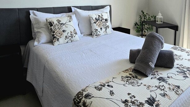 A bedroom with a bed, a ceiling fan, and three floral wall art pieces.