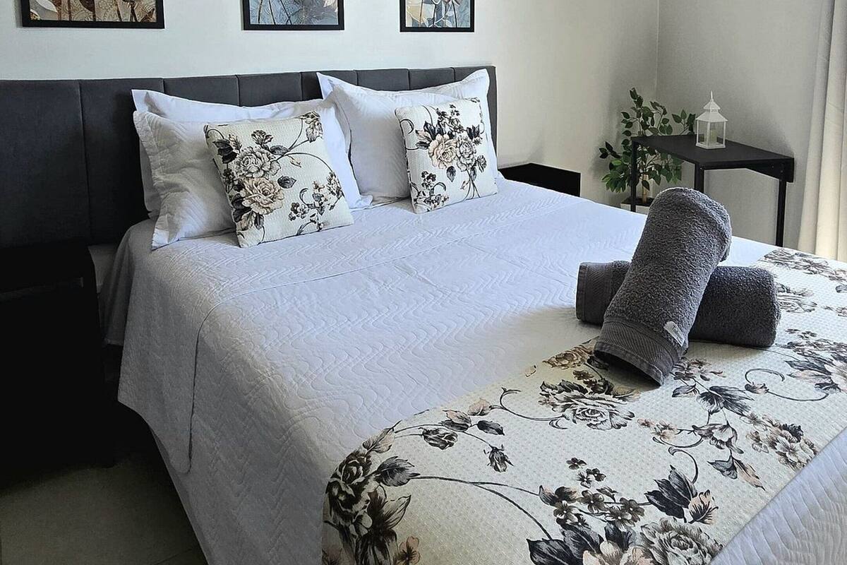 A bedroom with a bed, a ceiling fan, and three floral wall art pieces.