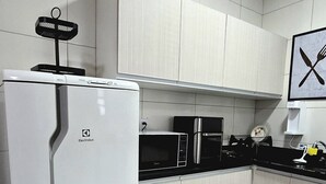 A kitchen with white cabinets, a white refrigerator, a microwave, and a sink. - Residencial Felicita (Barueri)