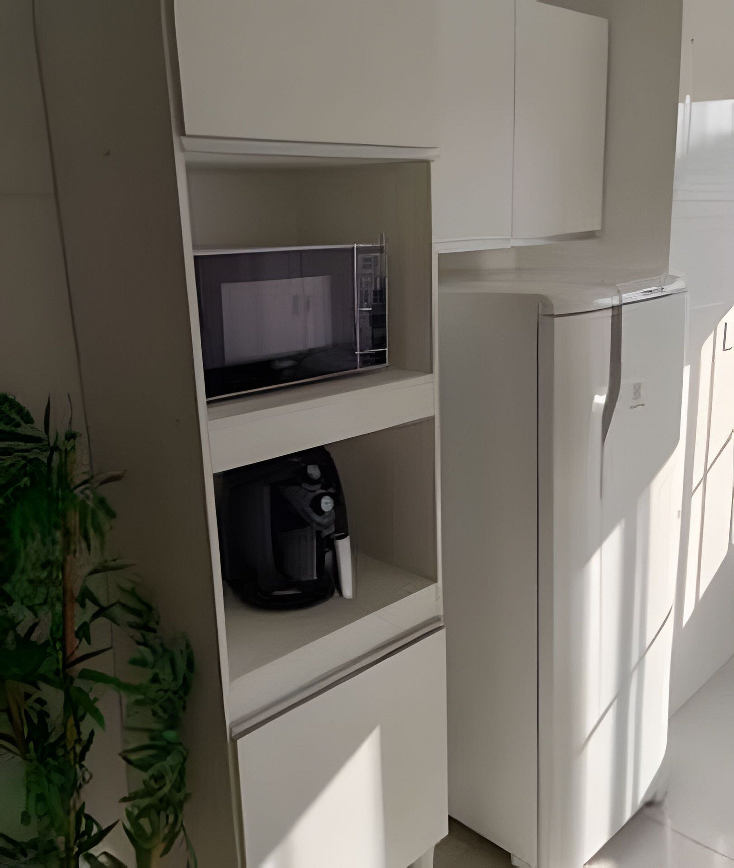 Une petite cuisine équipée d’un four à micro-ondes, d’une machine à café et d’un réfrigérateur blanc.