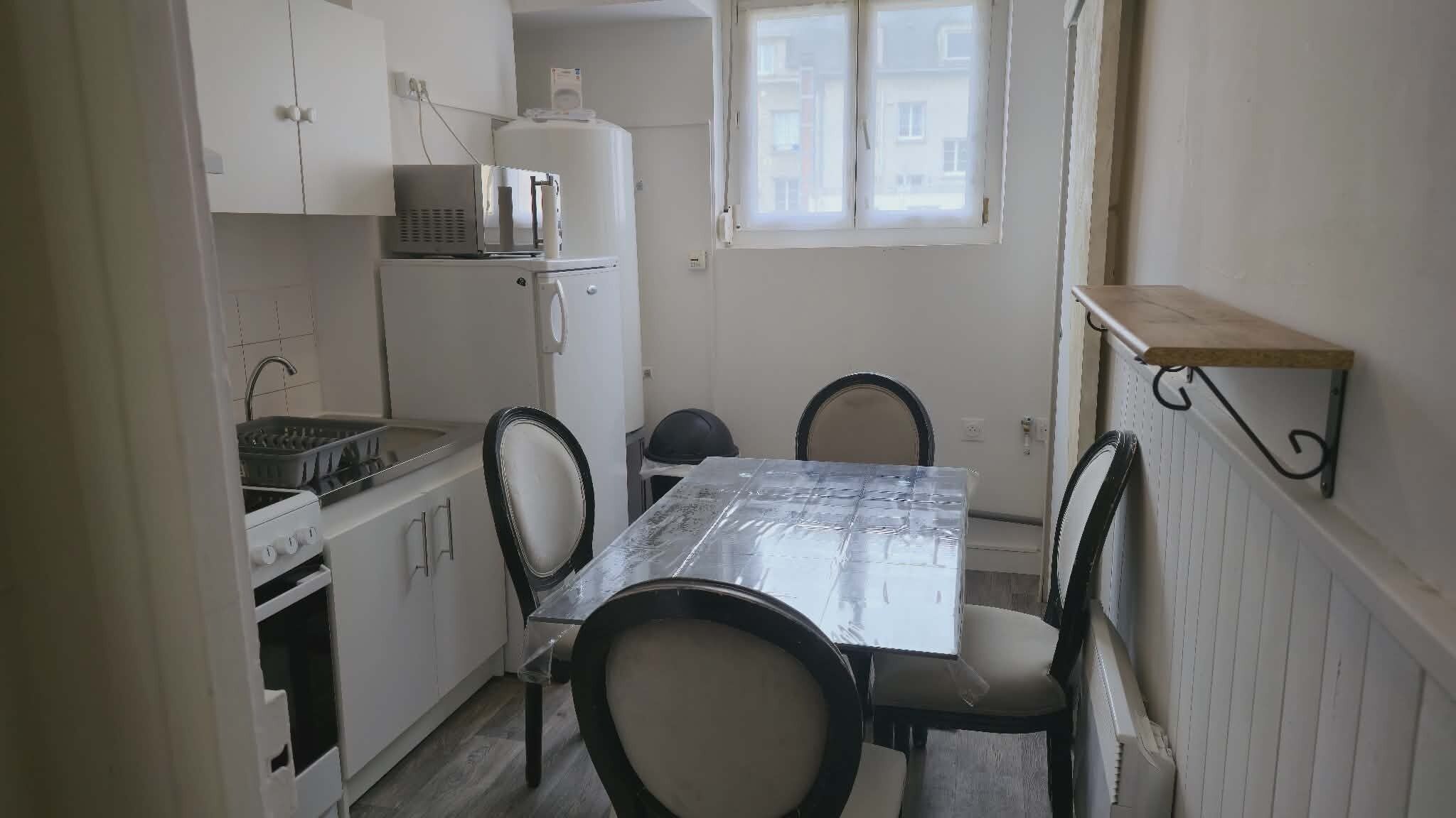 A compact kitchen with a dining table, chairs, a microwave, and a refrigerator.