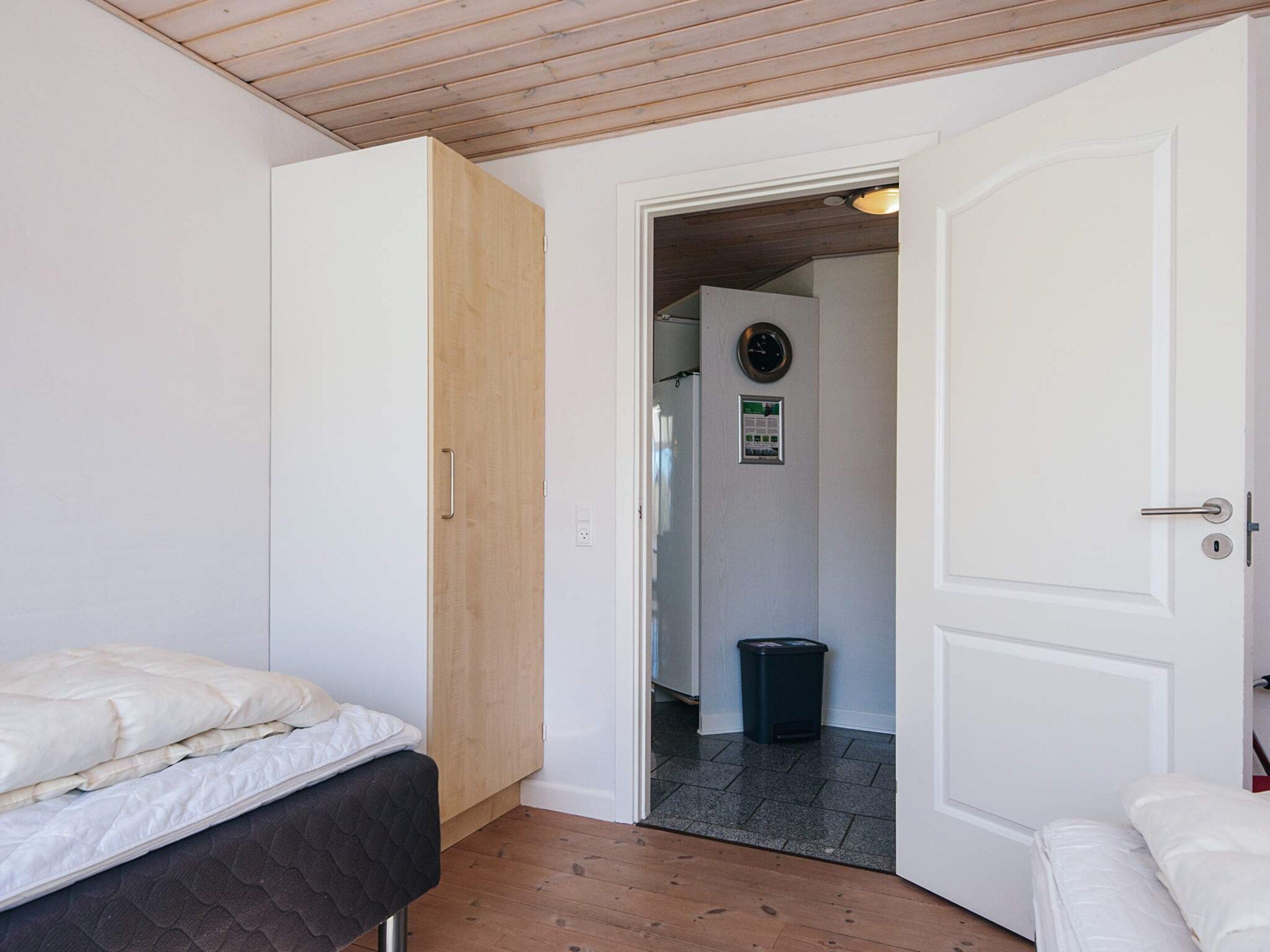Ein Schlafzimmer mit einem Bett, einem Kleiderschrank, einer Tür zu einem Badezimmer und einem Mülleimer.