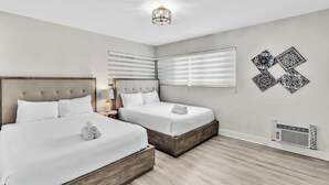 Una camera d'albergo con due letti, un lampadario, un condizionatore d'aria a muro e decorazioni murali.