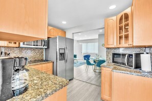 Una cocina moderna con encimeras de granito, electrodomésticos de acero inoxidable y armarios de madera.