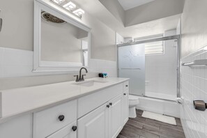 A modern bathroom with a white vanity, a large mirror, a shower enclosure, and a toilet. - Chic 2BR in Bay Harbor Islands near beach, shopping, and dining (Bay Harbor Islands)