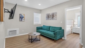 Una sala de estar moderna con un sofá color turquesa, una mesa de centro redonda y un televisor de pantalla plana montado en la pared.