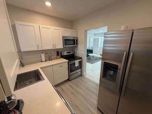A modern kitchen with white cabinets, stainless steel appliances, and a large refrigerator. - Modern 2BR in Bay Harbor Islands close to beach, shops, and dining (Bay Harbor Islands)