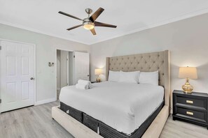A bedroom with a bed, a ceiling fan, a nightstand, and a door. - Elegant 2BR in Bay Harbor Islands near beach, Bal Harbour Shops, and dining (Bay Harbor Islands)
