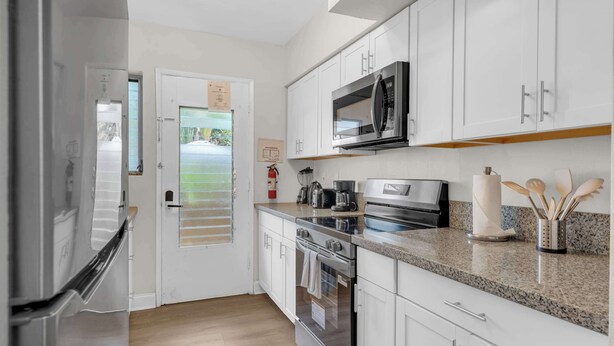 A modern kitchen with white cabinets, stainless steel appliances, and a granite countertop. - Boutique 2BR in Bay Harbor Islands close to beach, shops, and dining (Bay Harbor Islands)