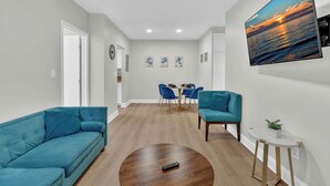 A modern living room with a sofa, coffee table, and a TV mounted on the wall. - Boutique 2BR in Bay Harbor Islands close to beach, shops, and dining (Bay Harbor Islands)
