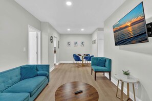 Una sala de estar moderna con un sofá, una mesa de centro y un televisor montado en la pared.