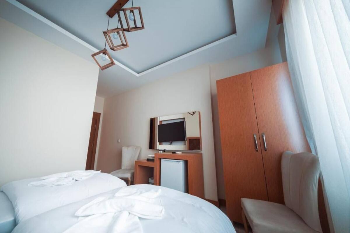 Ett hotellrum med en säng, ett skrivbord med en tv, en stol, en garderob och en taklampa.