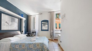 Une chambre à coucher avec un lit, une chaise, un bureau, un miroir et une fenêtre avec des rideaux.