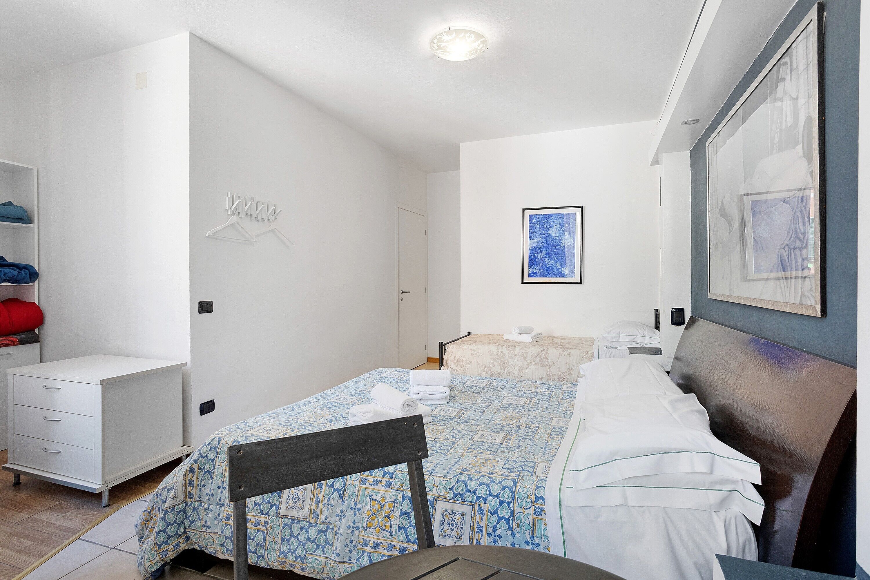 A bedroom with a bed, a desk, a chair, a wardrobe, and a bathroom.