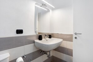 A bathroom with a white sink, two black soap dispensers, a mirror, and a toilet. - Room 'Charlot' in central Vernazza, Wi-Fi and air conditioning (Vernazza)
