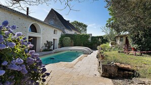 Une maison en pierre avec une piscine, un jardin et un petit bâtiment annexe.