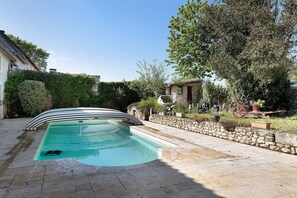 Une piscine à bords incurvés, avec des murs en pierre et des plantes en pot.
