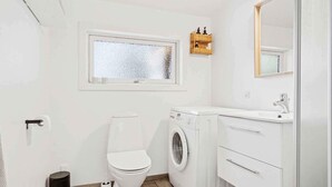 Egy kis méretű fürdőszoba, amelyben WC, mosógép és mosdókagyló található.