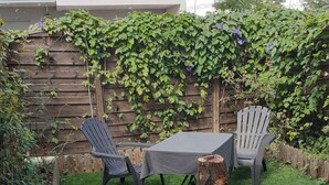 A patio with a table and two chairs, a wooden fence, and a tree stump. - Haven of peace (Montpellier)
