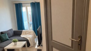 A living room with a sofa, a coffee table, a TV, and a door. - Haven of peace (Montpellier)