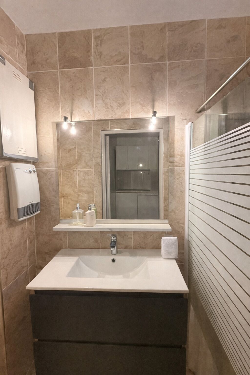 Un bagno con un lavandino grande, uno specchio, un erogatore di asciugamani e un porta asciugamani.