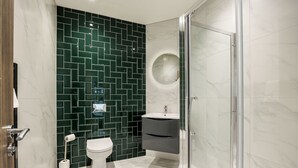 Un baño moderno con cabina de ducha de vidrio, inodoro, lavabo y tocador.