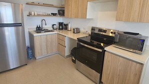 Eine moderne Küche mit einem Edelstahl-Kühlschrank, einem schwarzen Backofen, einer Mikrowelle und Holzschränken.